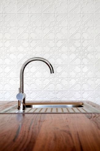 A sleek curved faucet is modern and clean against the backdrop of painted tin. What a beautiful way to add texture to a kitchen. I've always wanted a gilded tin ceiling, or one with peeling, distressed paint.