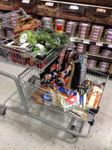 A moderately full cart. Mostly greens and whole grains. Lots of re-usable shopping bags. 